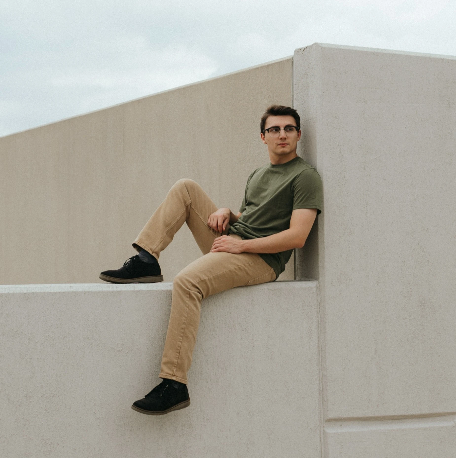 Lorenzo posing by sitting on a parking structure ledge